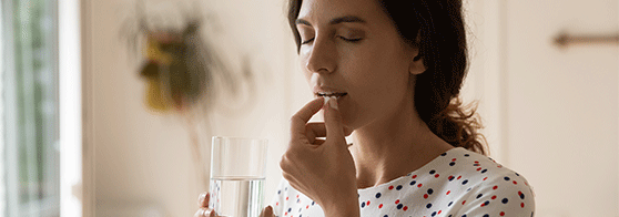 Femme prenant un médicament avec un verre d'eau
